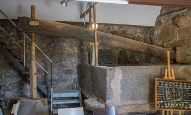 Antique wine press with a wooden beam and granite