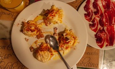 Selection of Galician tapas on rustic plates with white wine.