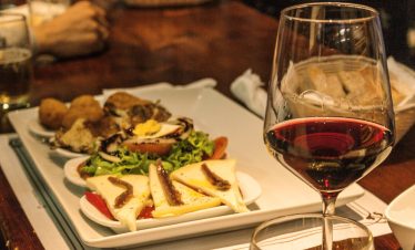 Glass of red wine alongside a small tapa at a bar in Santiago de Compostela.