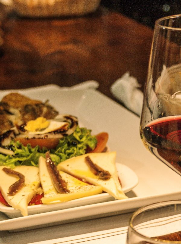 Glass of red wine alongside a small tapa at a bar in Santiago de Compostela.