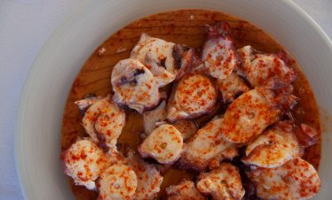 Close-up of a dish of pulpo a la gallega with a wine pairing.